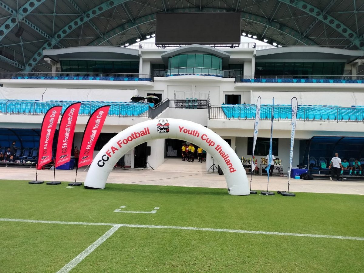 ซุ้มโค้งและธง CCFA บนสนามในสนามกีฬา มีอัฒจันทร์อยู่ด้านหลัง