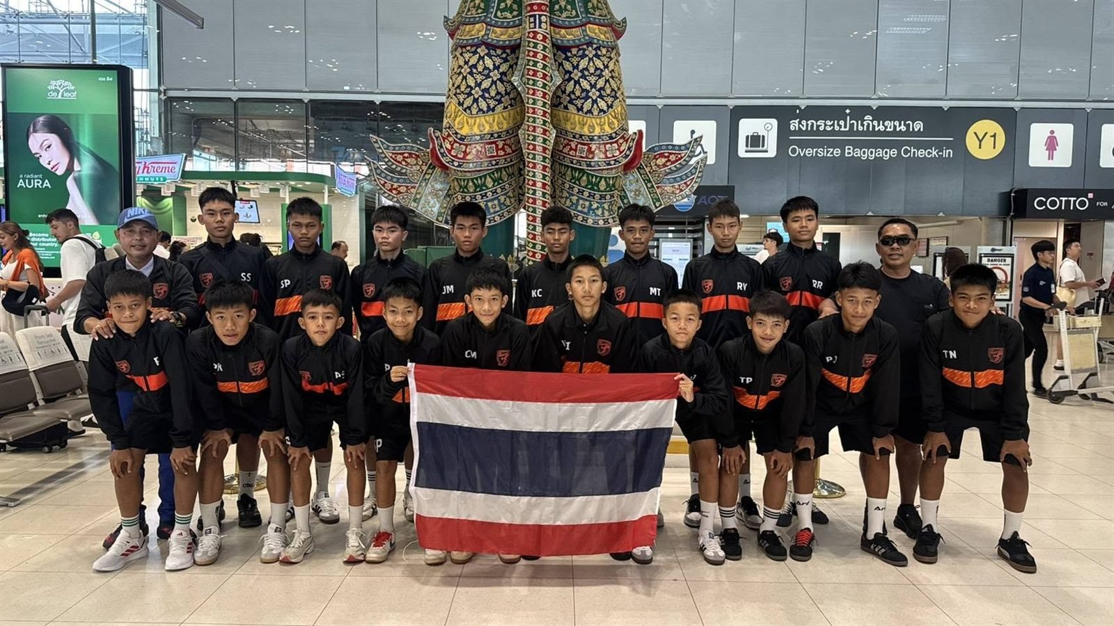 ทีมเยาวชนและโค้ชถือธงชาติไทย ที่ท่าอากาศยานสุวรรณภูมิ กรุงเทพฯ